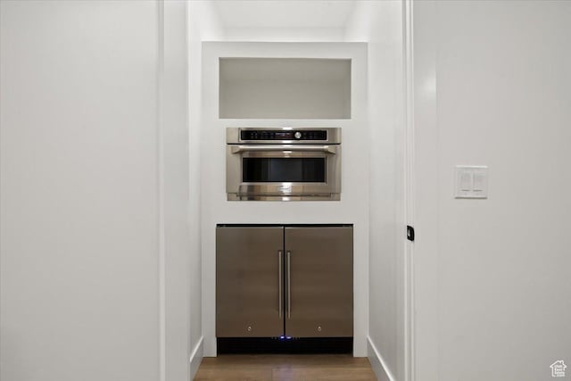 kitchen view of stainless steel appliances, wood finished floors, and baseboards