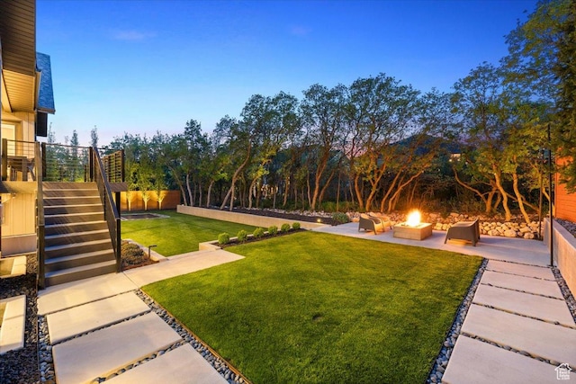 view of grassy yard with a fire pit, a patio, and stairway