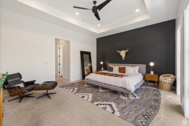 carpeted bedroom featuring recessed lighting, an accent wall, ceiling fan, a tray ceiling, and baseboards