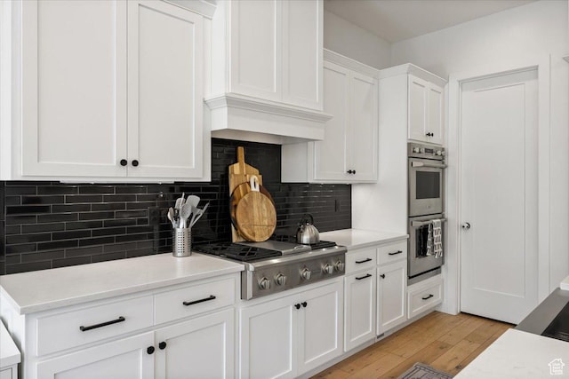 kitchen featuring stainless steel appliances, white cabinets, light wood-type flooring, and light countertops