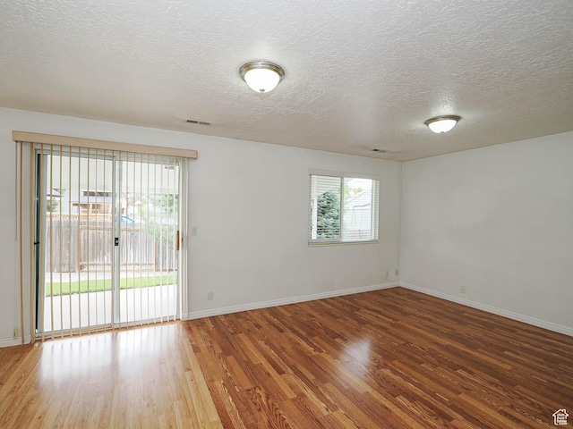 spare room featuring wood finished floors, a textured ceiling, and baseboards