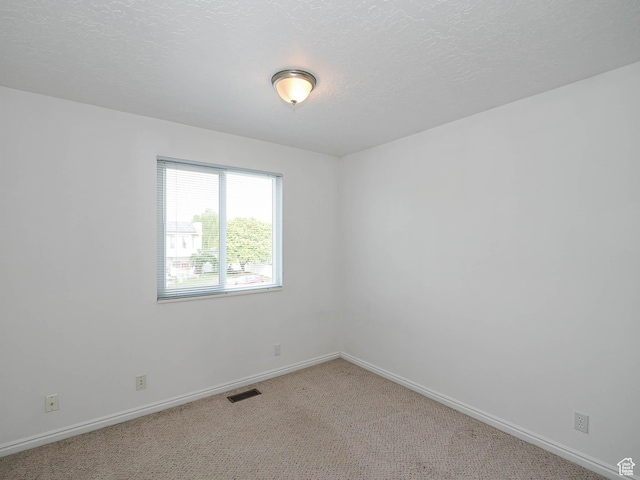 empty room featuring baseboards and light carpet