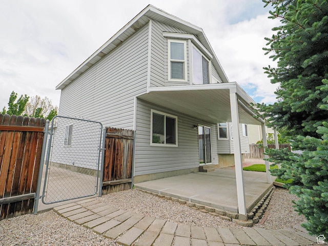 rear view of house with a gate, a patio, and fence