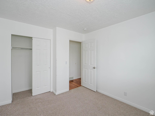 unfurnished bedroom featuring carpet, a closet, baseboards, and a textured ceiling