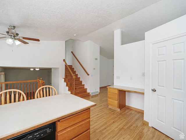 kitchen featuring light wood-style floors, ceiling fan, black dishwasher, light countertops, and a textured ceiling