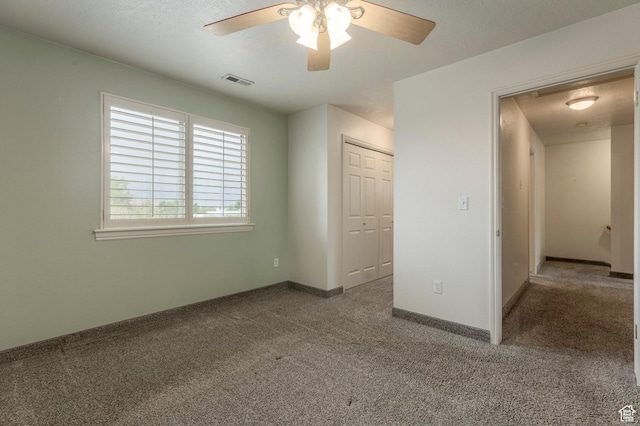 unfurnished bedroom with carpet floors, a closet, baseboards, and a ceiling fan