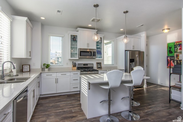 kitchen featuring stainless steel appliances, a sink, a breakfast bar area, light countertops, and recessed lighting