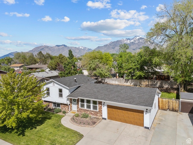 view of front of property featuring an attached garage, a mountain view, driveway, and roof with shingles