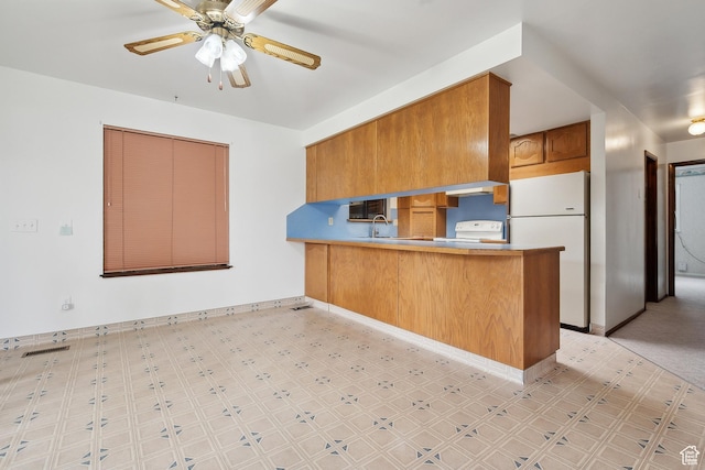 2268 W 5300 S, Roy, UT 84067 - kitchen with freestanding refrigerator, a peninsula, light flooring, brown cabinets, and a ceiling fan