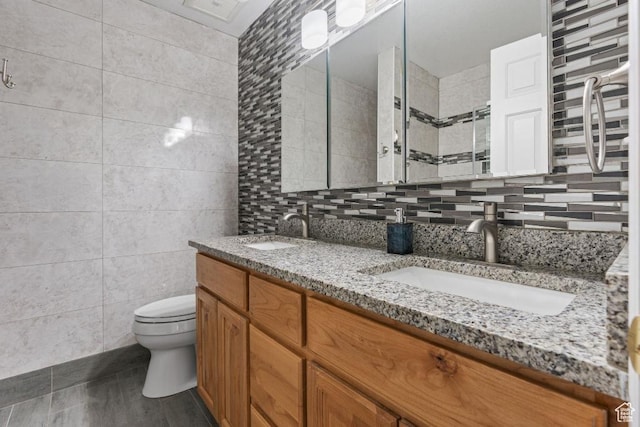 bathroom with tile walls, toilet, double vanity, tile patterned flooring, and tiled shower