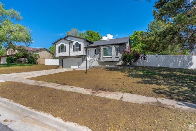 tri-level home with concrete driveway, fence, and a garage