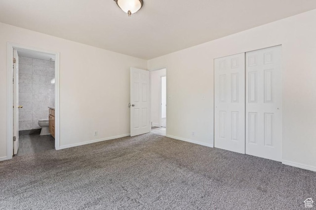 unfurnished bedroom featuring carpet, a closet, baseboards, and ensuite bath