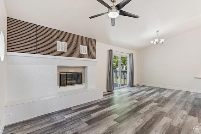 unfurnished living room with a chandelier, a glass covered fireplace, wood finished floors, ceiling fan, and high vaulted ceiling