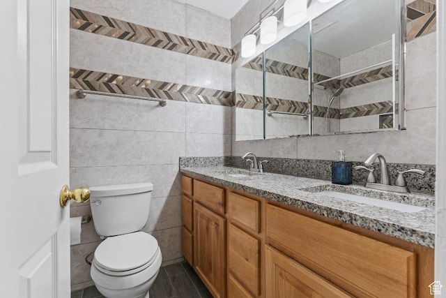 bathroom with toilet, a tile shower, double vanity, and tile walls