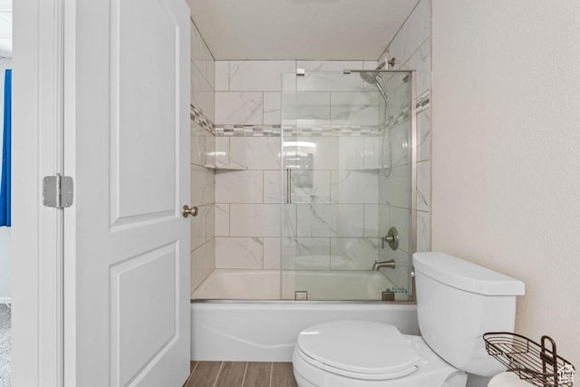 bathroom featuring toilet, bath / shower combo with glass door, and wood finished floors