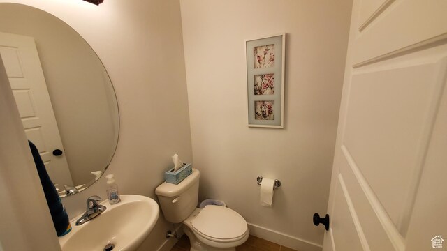 bathroom with a sink, toilet, and baseboards