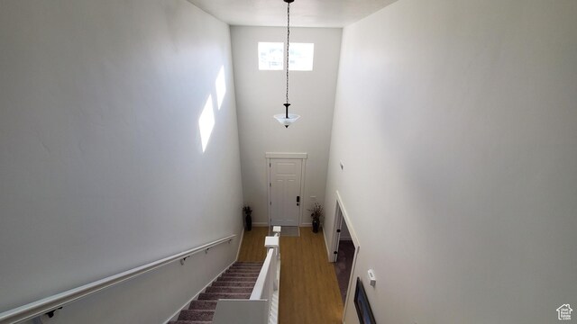 stairs with wood finished floors, a high ceiling, and baseboards