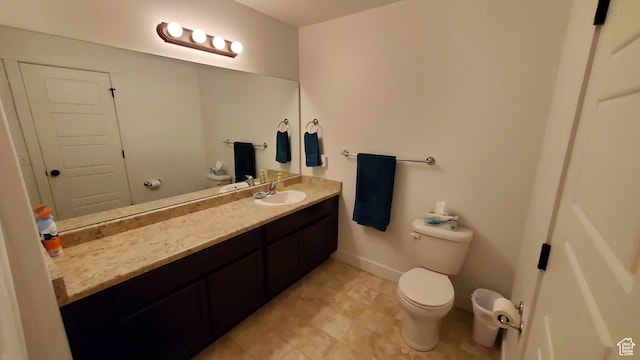 bathroom featuring toilet, vanity, and baseboards