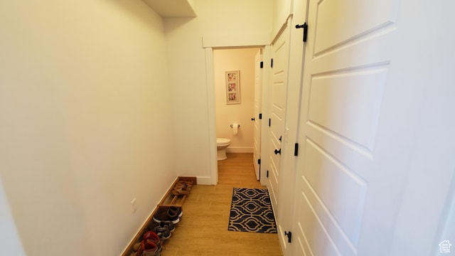 hall with light wood-type flooring and baseboards