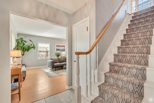 stairway with baseboards, crown molding, and wood finished floors