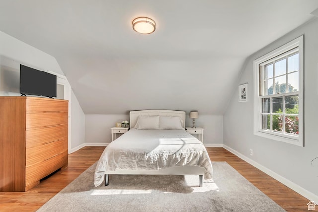 bedroom featuring baseboards, vaulted ceiling, and wood finished floors