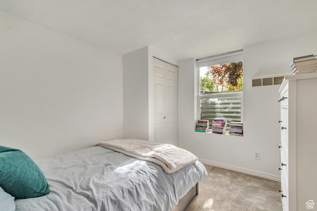 bedroom with light carpet, a closet, and baseboards