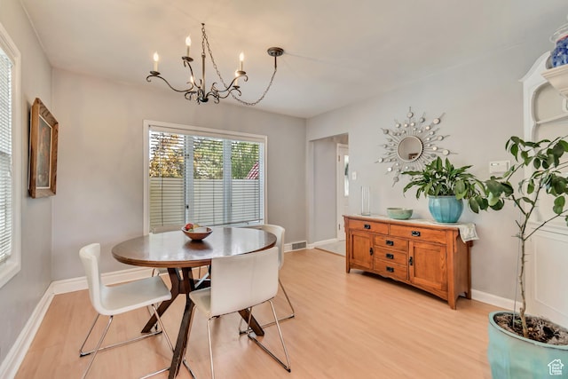 dining space with light wood-style floors, a chandelier, and baseboards