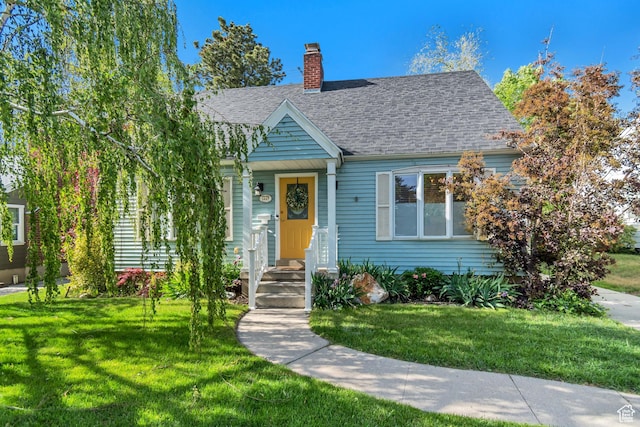 view of front facade featuring a chimney, a front lawn, and a shingled roof