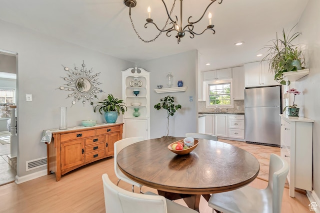 dining room with a chandelier, light wood finished floors, and recessed lighting