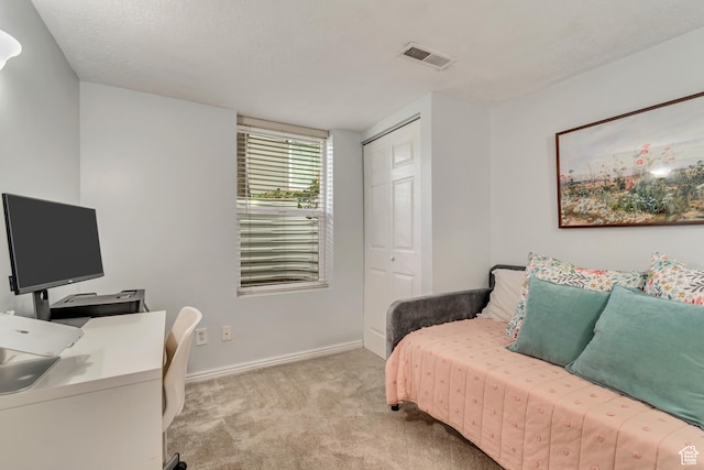 bedroom with carpet floors, a closet, an office area, and baseboards
