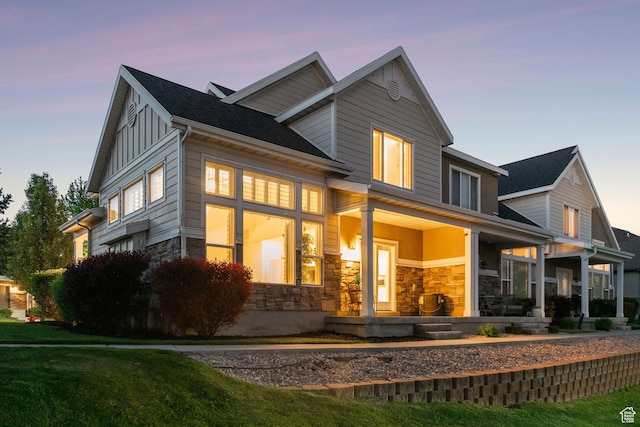 82 E Danta Dr S, Draper, UT 84020 - back of property at dusk with stone siding, a porch, and board and batten siding