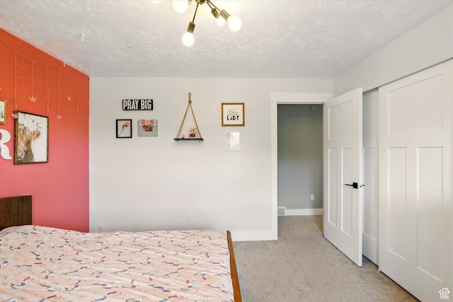 bedroom featuring light colored carpet, a closet, a textured ceiling, and baseboards