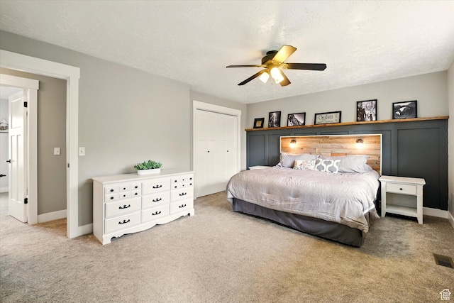 carpeted bedroom with ceiling fan, a closet, and baseboards