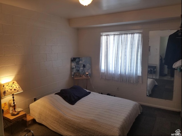bedroom featuring concrete block wall