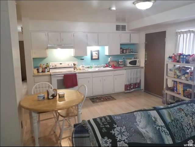 kitchen with white appliances, a sink, under cabinet range hood, light wood-style floors, and white cabinets