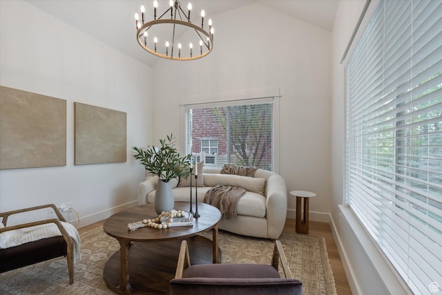 living area with wood finished floors, a chandelier, high vaulted ceiling, and baseboards
