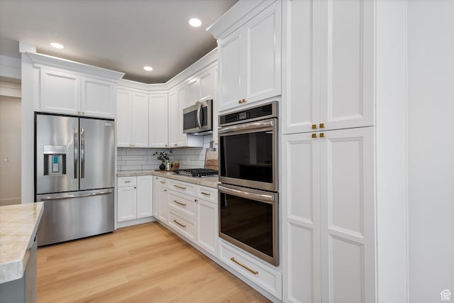 kitchen with stainless steel appliances, light countertops, decorative backsplash, white cabinetry, and recessed lighting
