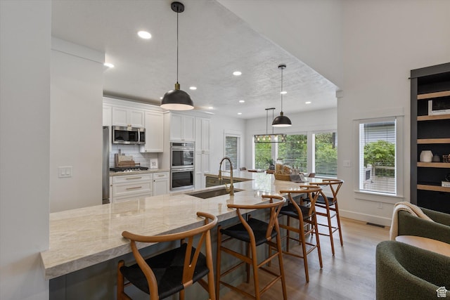 kitchen featuring a sink, stainless steel appliances, light wood-style floors, white cabinetry, and recessed lighting