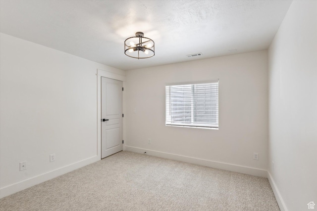 empty room with light carpet, a chandelier, and baseboards