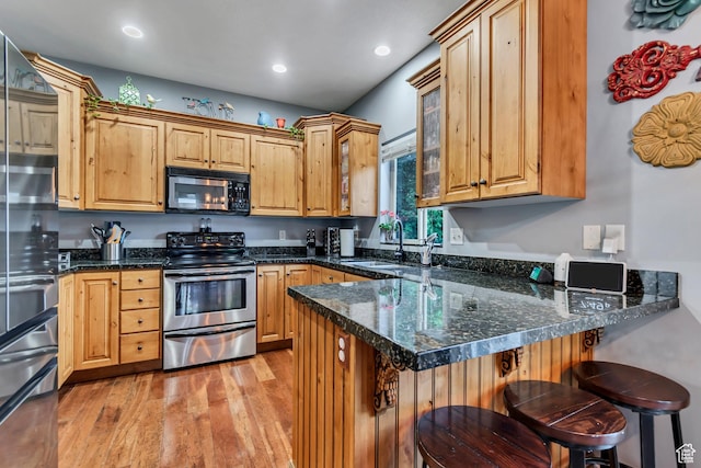 5414 W Island Creek Dr S, West Jordan, UT 84081 - kitchen with stainless steel appliances, a sink, a peninsula, light wood-style flooring, and a breakfast bar area