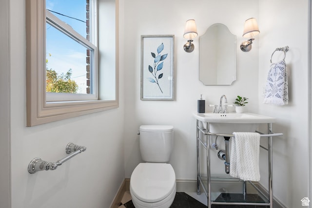 half bath featuring baseboards and toilet