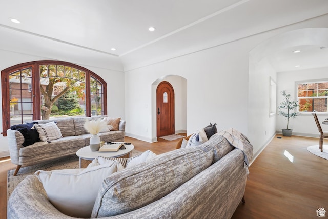 living area featuring arched walkways, baseboards, wood finished floors, and recessed lighting
