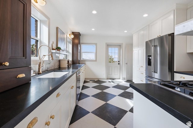 kitchen with stainless steel appliances, a sink, dark flooring, dark countertops, and recessed lighting