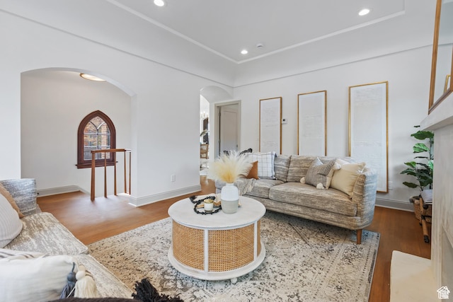 living area with arched walkways, wood finished floors, baseboards, and recessed lighting