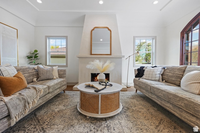 living area with wood finished floors, recessed lighting, and a warm lit fireplace