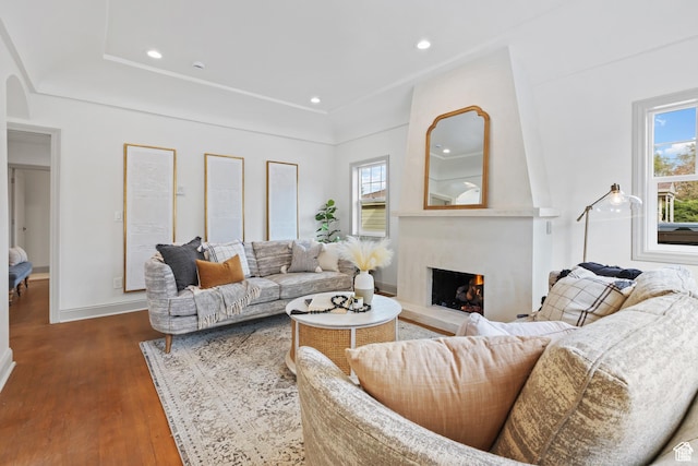living room featuring dark wood-style floors, a lit fireplace, baseboards, recessed lighting, and arched walkways