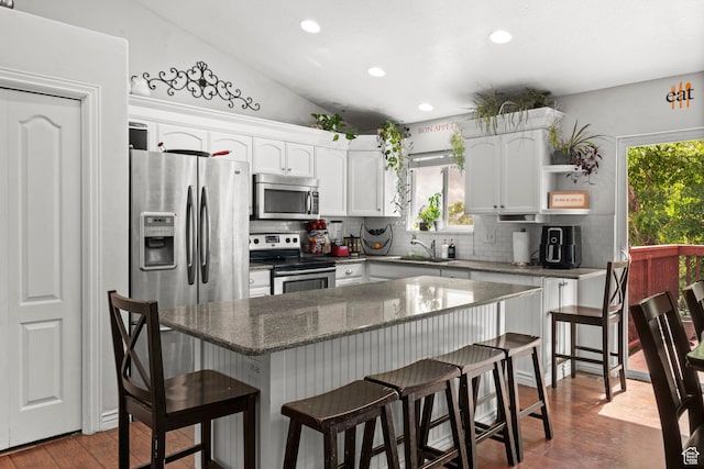 2142 Alaska Ave, Provo, UT 84606 - kitchen with stainless steel appliances, a sink, decorative backsplash, white cabinets, and a kitchen breakfast bar