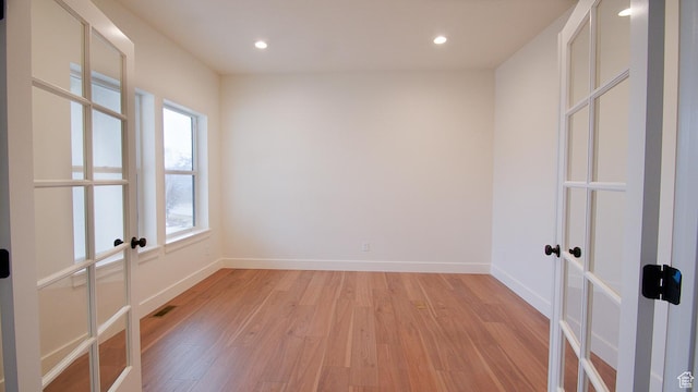 spare room featuring french doors, plenty of natural light, light wood-style flooring, baseboards, and recessed lighting