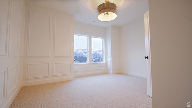 spare room with a decorative wall and light carpet