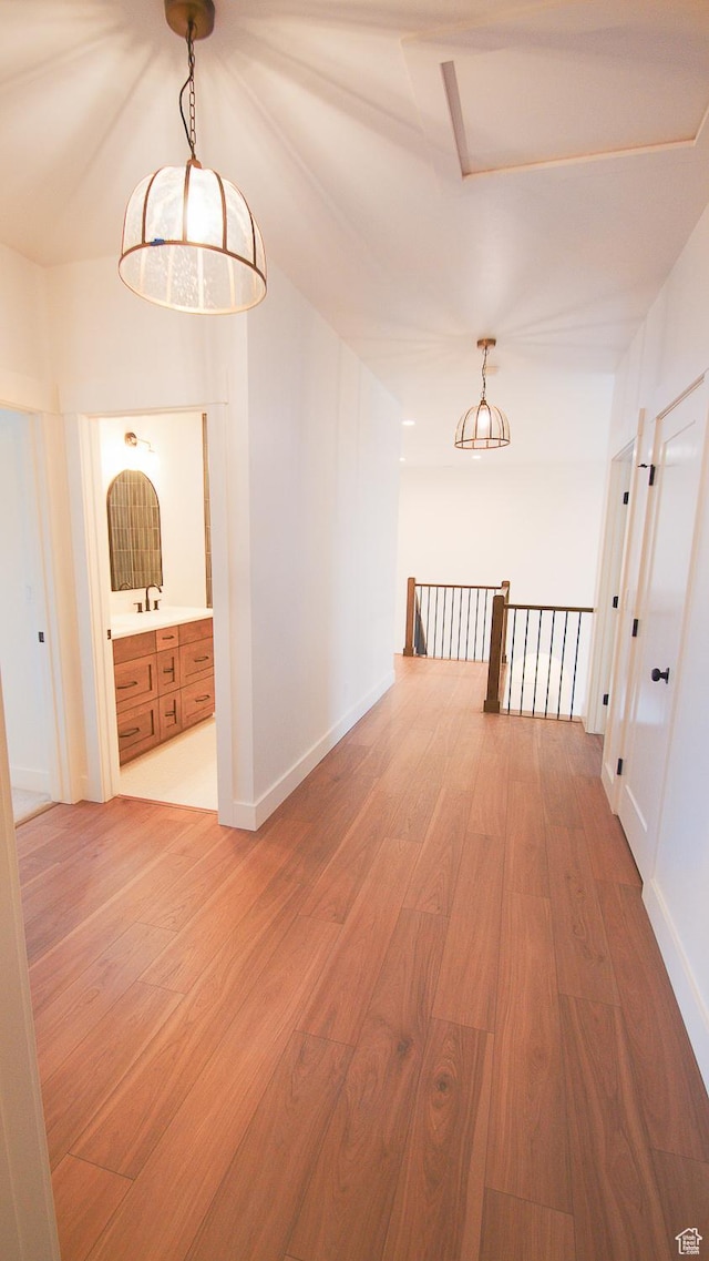 hallway with light wood-style floors, an upstairs landing, and baseboards